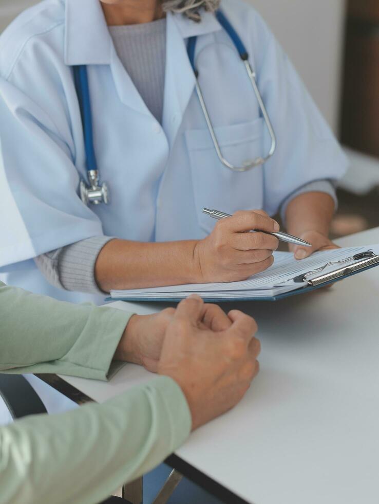 Doctor giving hope. Close up shot of young female physician leaning forward to smiling elderly lady patient holding her hand in palms. Woman caretaker in white coat supporting encouraging old person photo