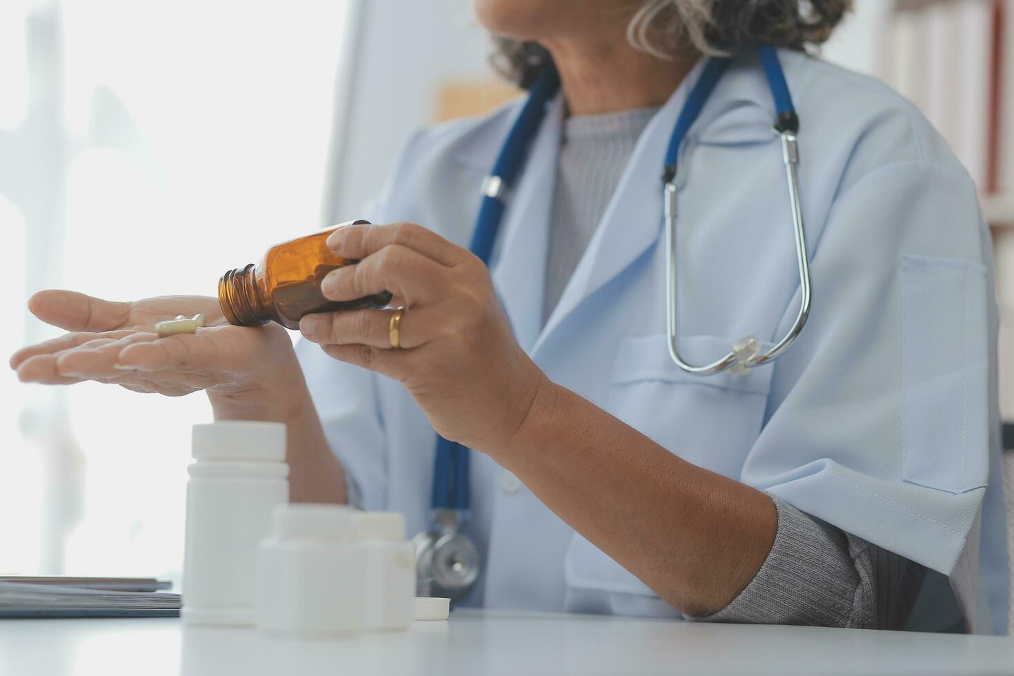 Doctor giving hope. Close up shot of young female physician leaning forward to smiling elderly lady patient holding her hand in palms. Woman caretaker in white coat supporting encouraging old person photo