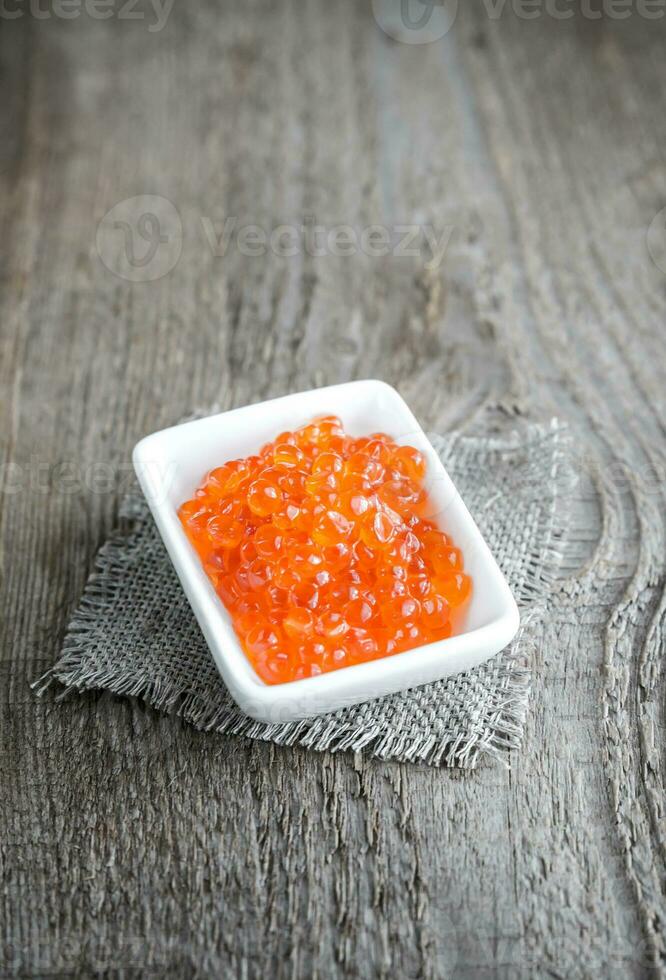 cuenco de caviar rojo sobre la mesa de madera foto