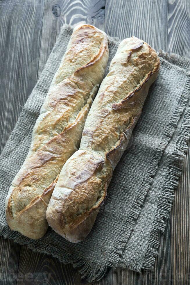 Two baguettes on the wooden background photo