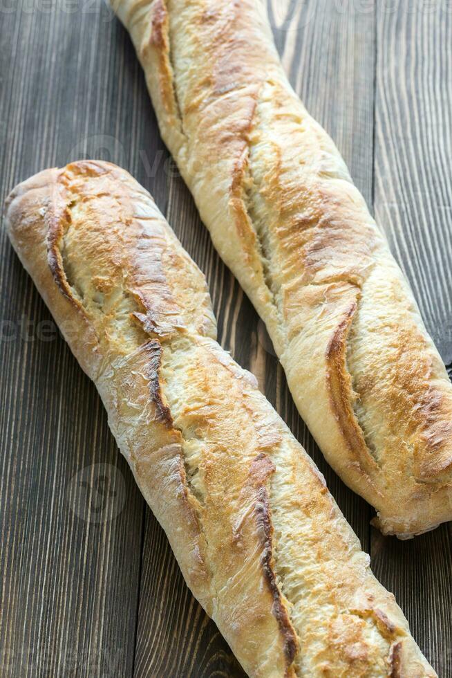 Two baguettes on the wooden background photo