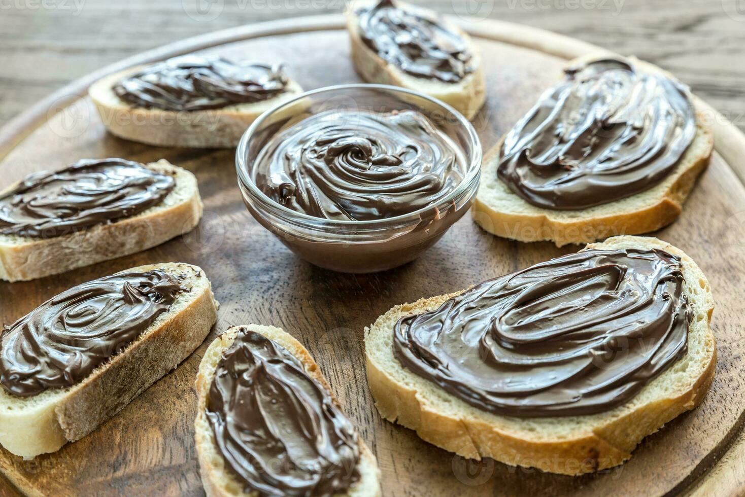 Slices of baguette with chocolate cream on the wooden board photo