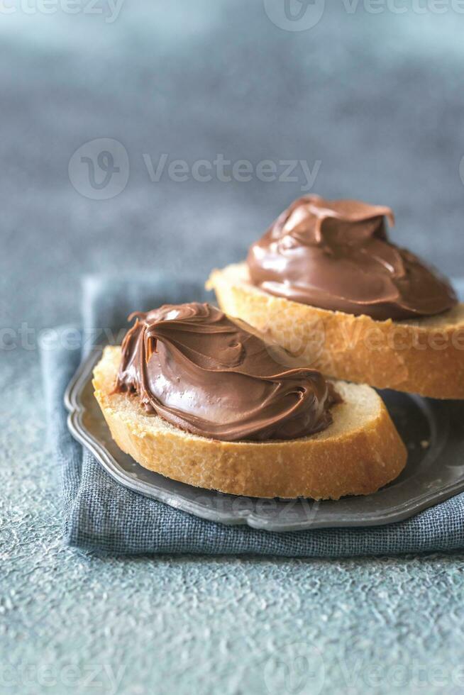 Slice of baguette with chocolate cream on the saucer photo