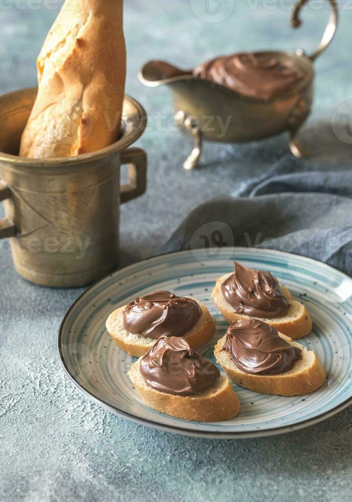 Slices of baguette with chocolate cream on the plate photo