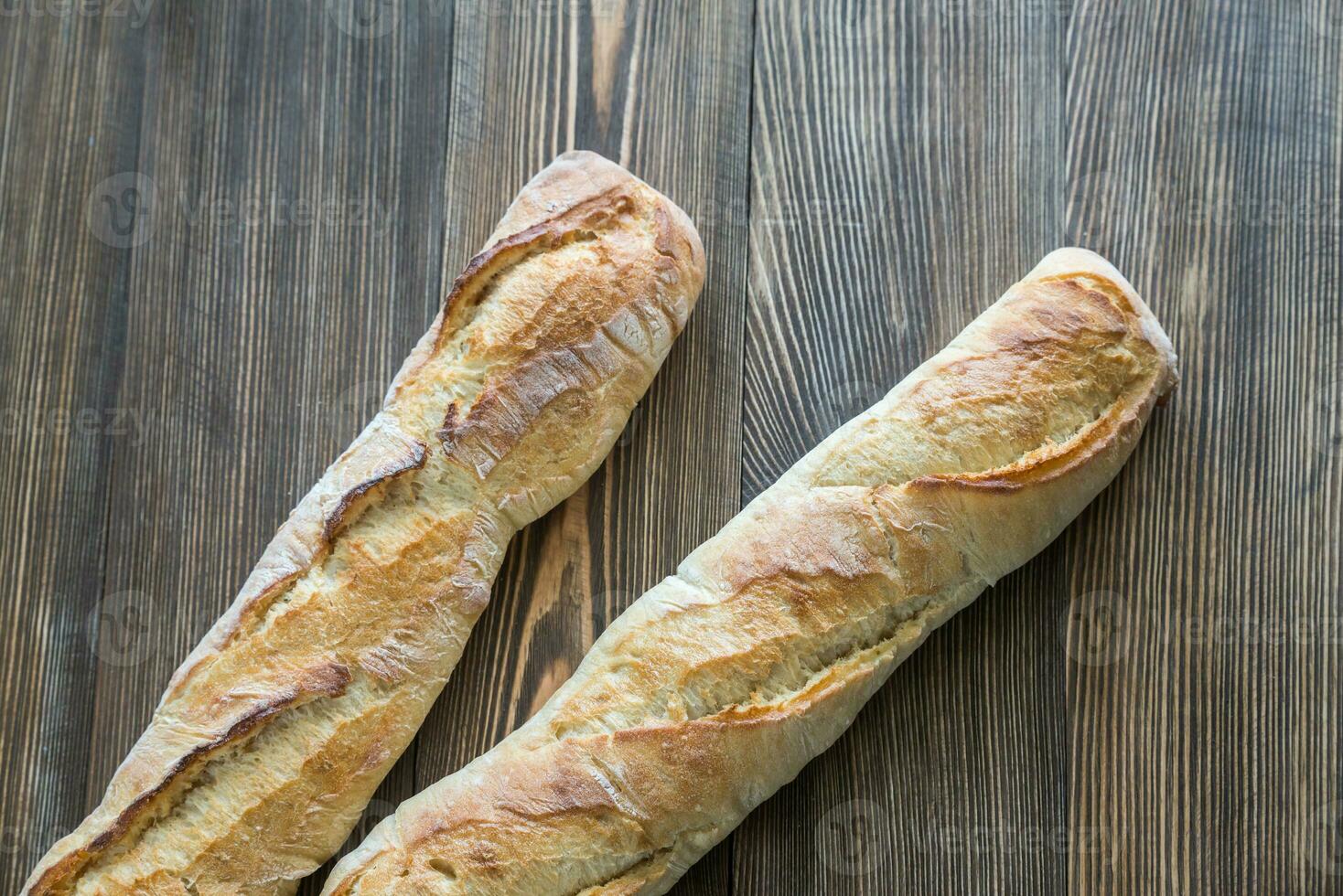 Two baguettes on the wooden background photo