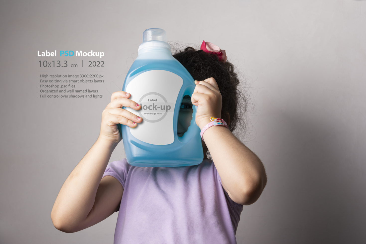 Little girl holding a cloth detergent liquid bottle at front of her face psd