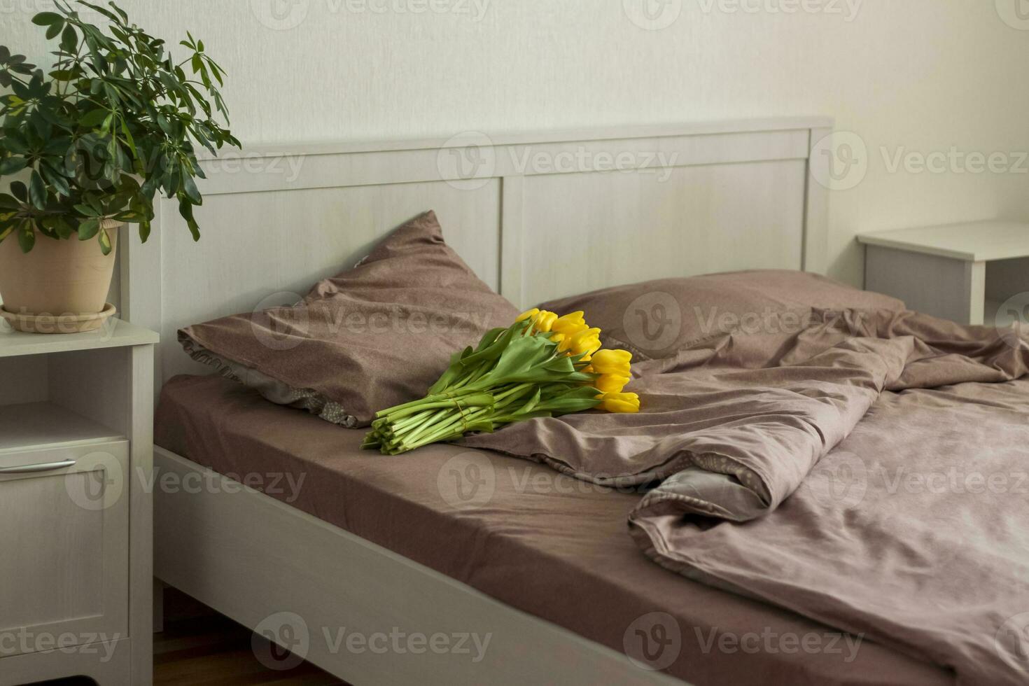 en el cama es un ramo de flores de amarillo tulipanes ramo de flores de Fresco tulipanes primavera flores en el dormitorio interior. el concepto de primavera o día festivo, marzo 8, internacional De las mujeres día foto