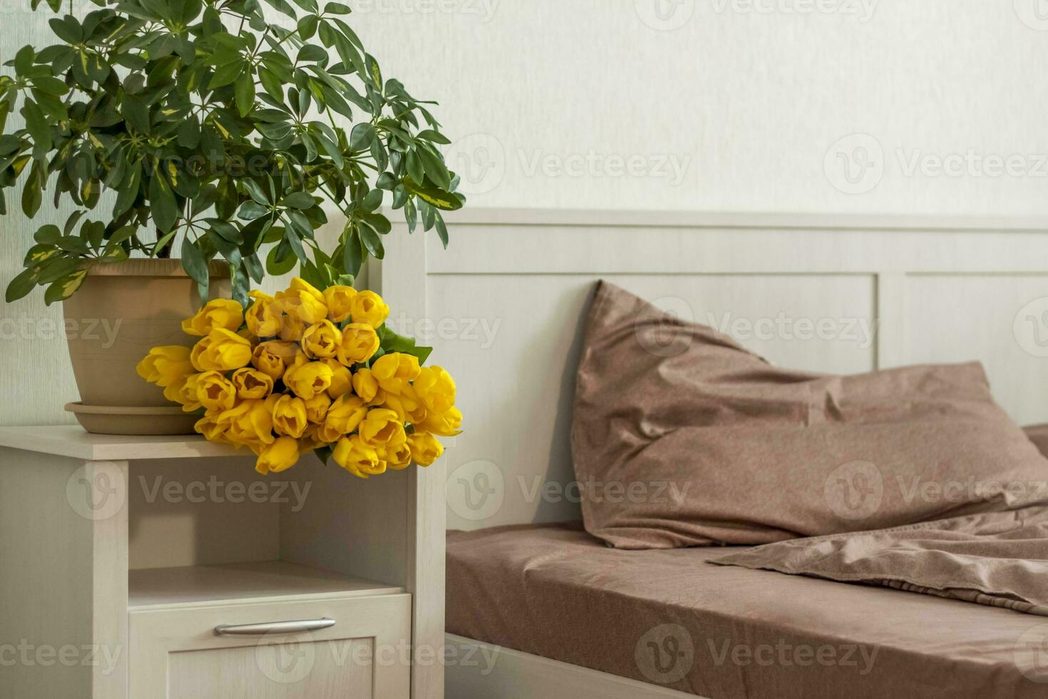 On the bed is a bouquet of yellow tulips. Bouquet of fresh tulips. Spring flowers in the bedroom interior. The concept of spring or holiday, March 8, International Women's Day photo