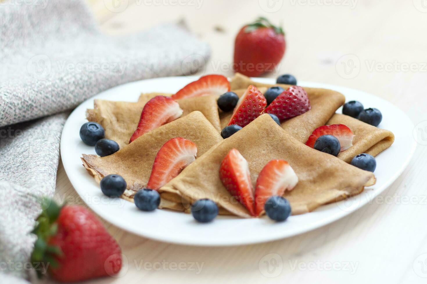 Pancakes with blueberries and strawberries on the table. Traditional food for Maslenitsa photo