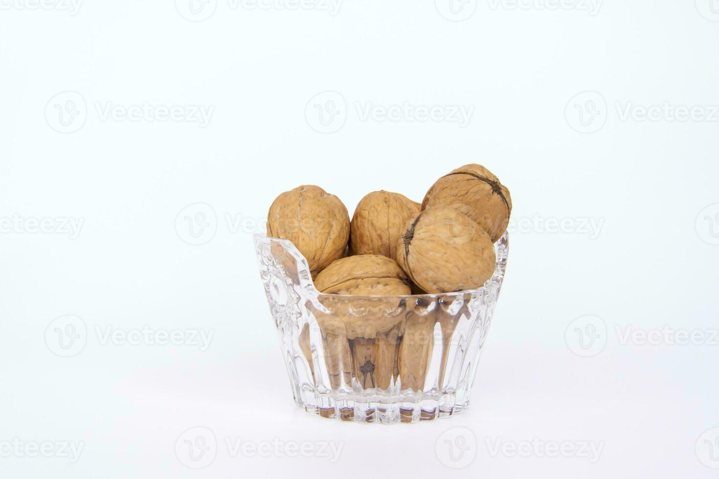 Walnuts in a shell on a white background in a crystal vase. Healthy nuts. photo