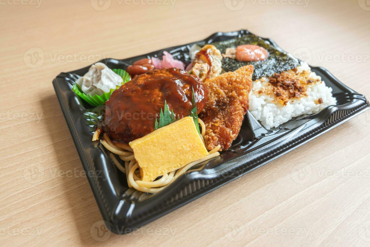 Japanese bento set lunch box of hamburger steak, seaweed on rice, fried fish and Japanese rolled omelet photo