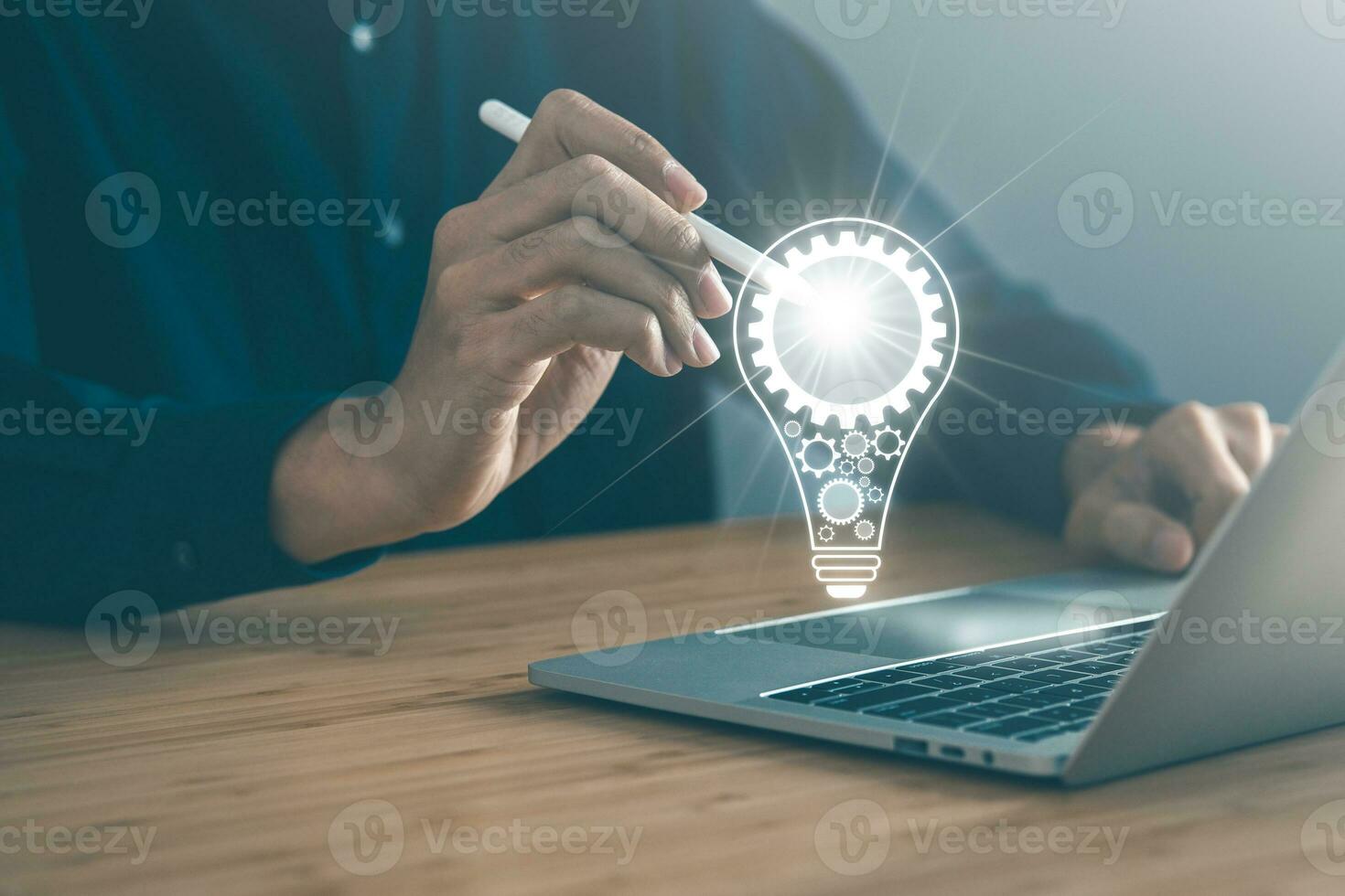 Business man pointing light bulb with laptop, keyboard and mouse background. New idea, innovation technology and creativity concept. photo