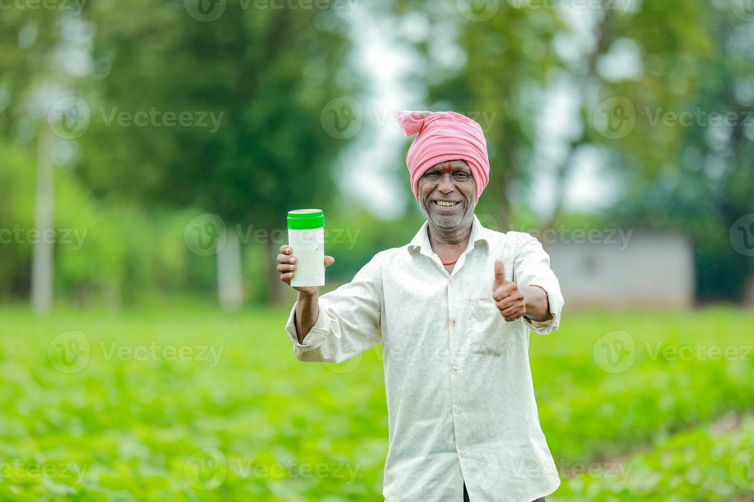 Indian happy farmer holding empty Bottle in hands, happy farmer showing white Bottle photo