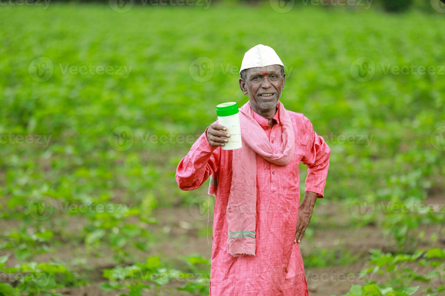 Indian happy farmer holding empty Bottle in hands, happy farmer showing white Bottle photo