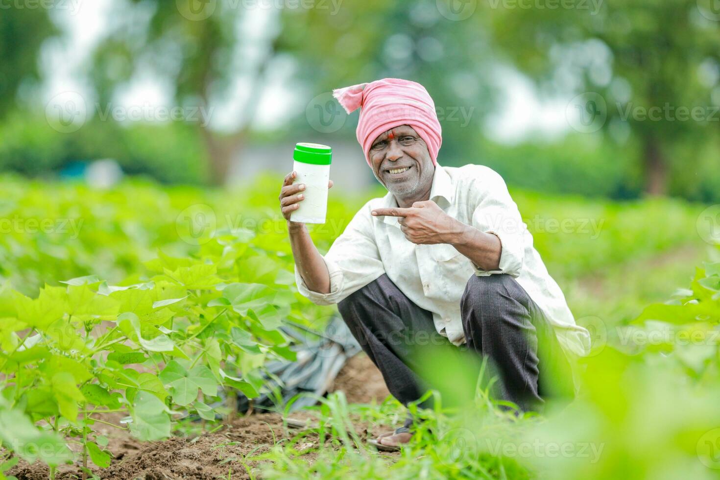 Indian happy farmer holding empty Bottle in hands, happy farmer showing white Bottle photo