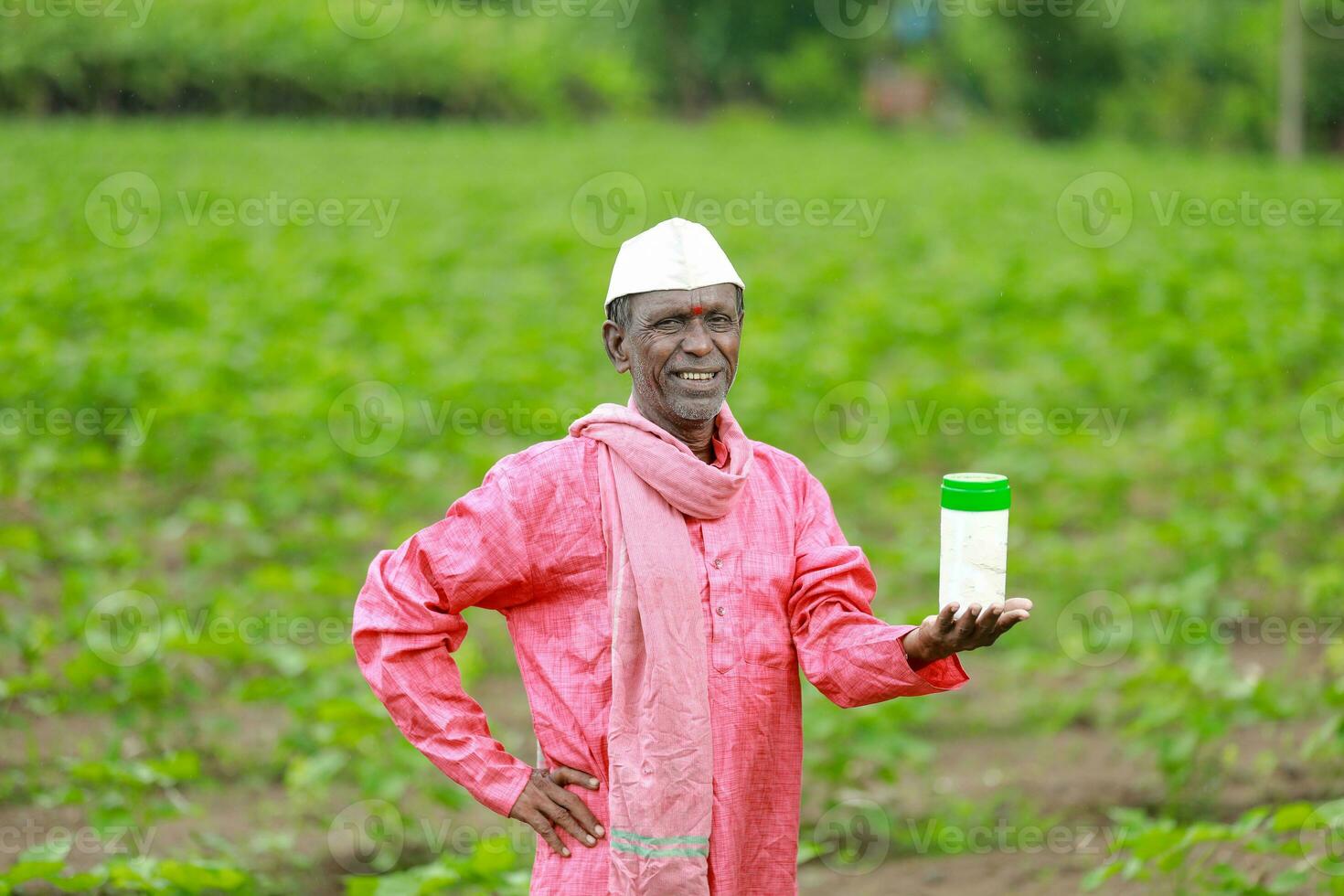 Indian happy farmer holding empty Bottle in hands, happy farmer showing white Bottle photo