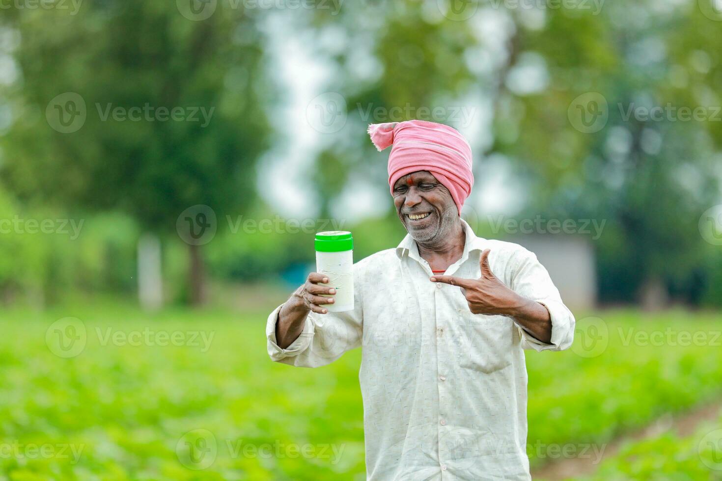 Indian happy farmer holding empty Bottle in hands, happy farmer showing white Bottle photo