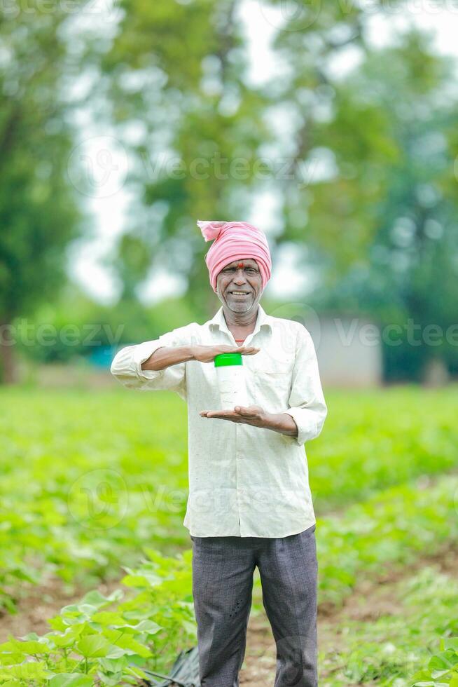 Indian happy farmer holding empty Bottle in hands, happy farmer showing white Bottle photo