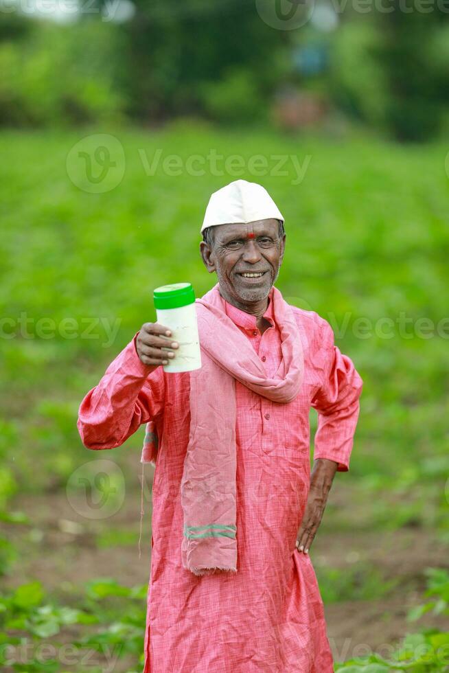 Indian happy farmer holding empty Bottle in hands, happy farmer showing white Bottle photo