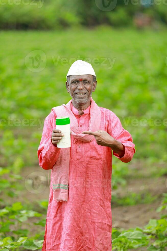 Indian happy farmer holding empty Bottle in hands, happy farmer showing white Bottle photo