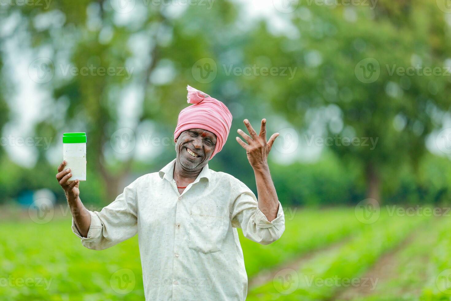 Indian happy farmer holding empty Bottle in hands, happy farmer showing white Bottle photo