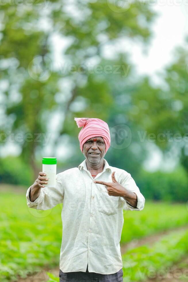 Indian happy farmer holding empty Bottle in hands, happy farmer showing white Bottle photo