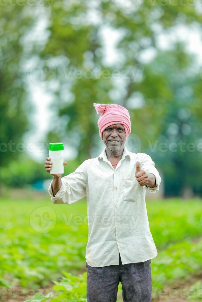 Indian happy farmer holding empty Bottle in hands, happy farmer showing white Bottle photo