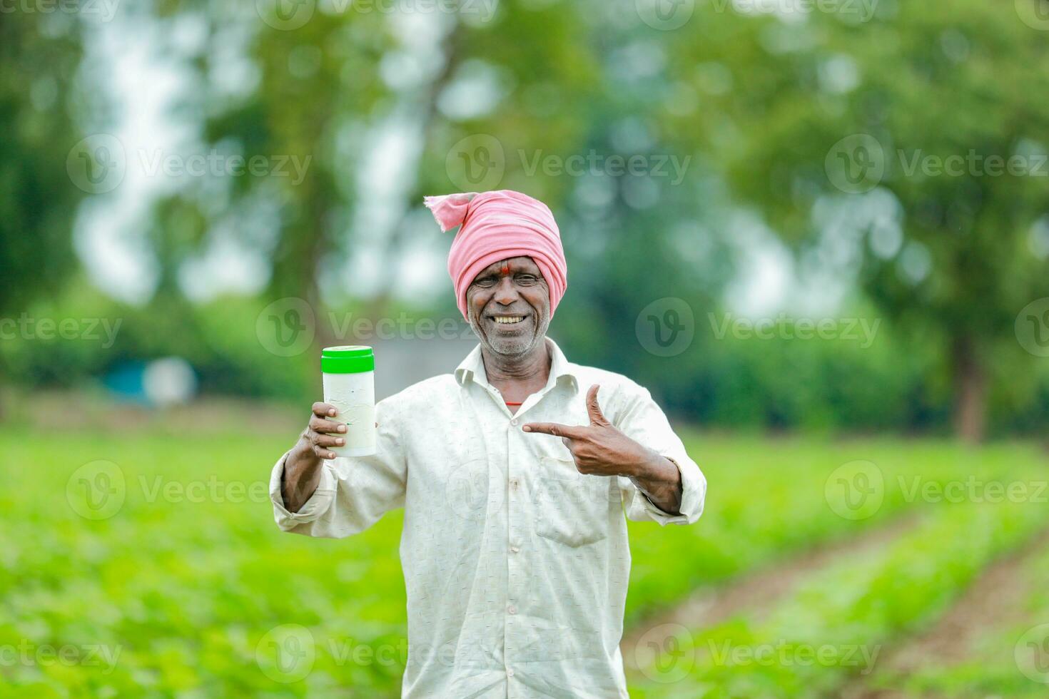 Indian happy farmer holding empty Bottle in hands, happy farmer showing white Bottle photo