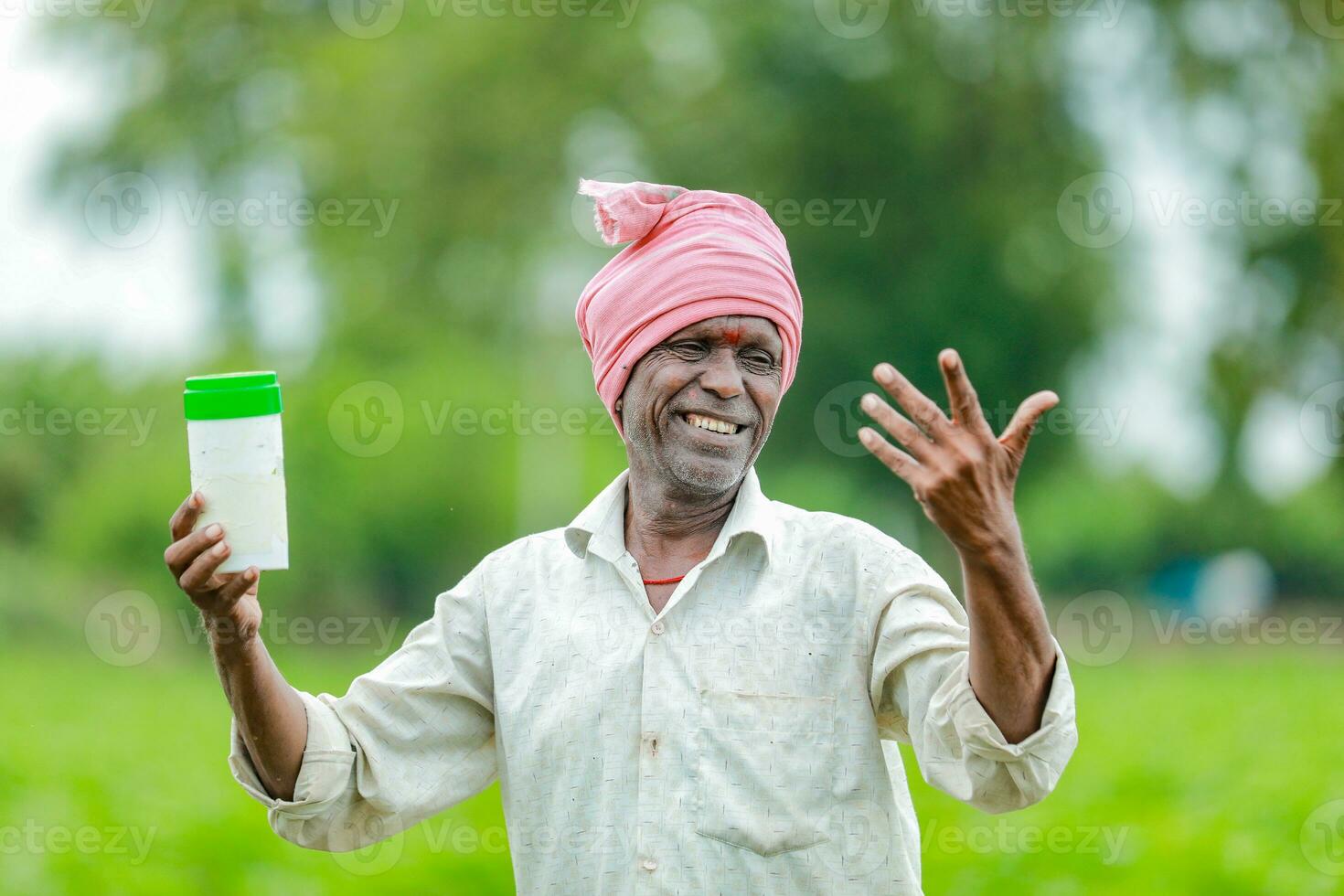 Indian happy farmer holding empty Bottle in hands, happy farmer showing white Bottle photo