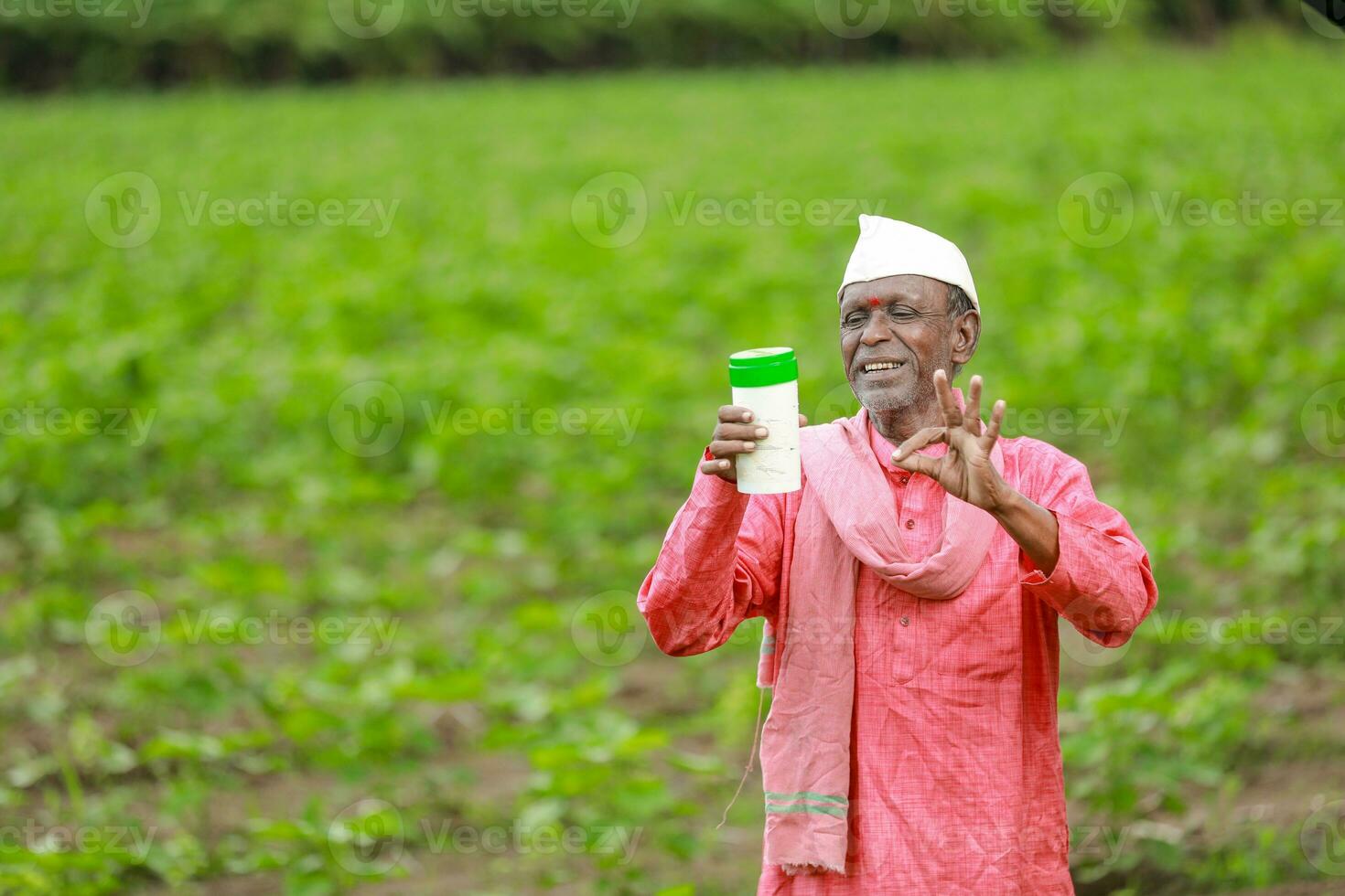Indian happy farmer holding empty Bottle in hands, happy farmer showing white Bottle photo