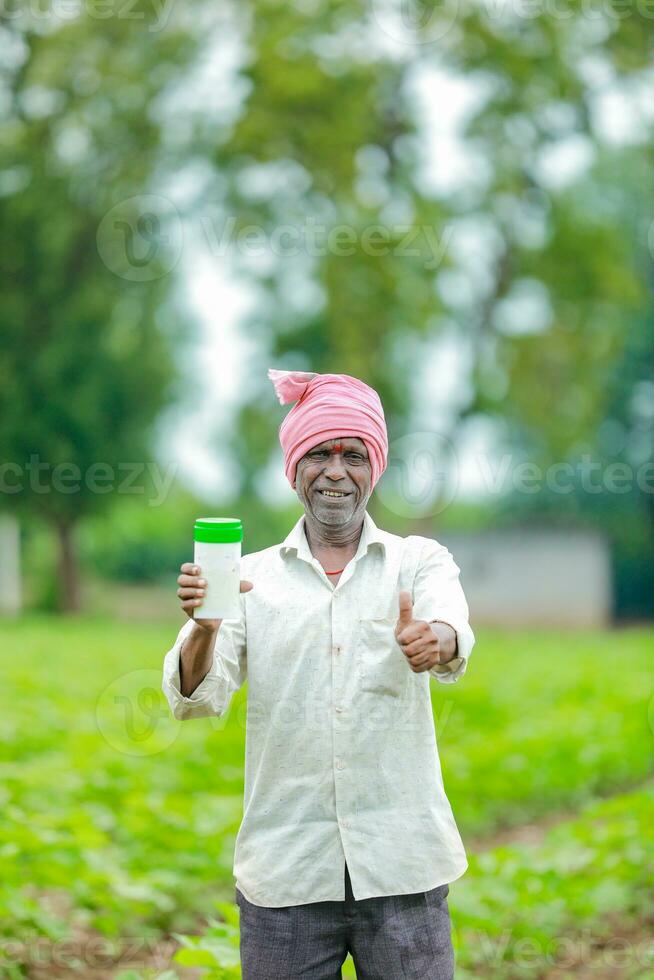 Indian happy farmer holding empty Bottle in hands, happy farmer showing white Bottle photo