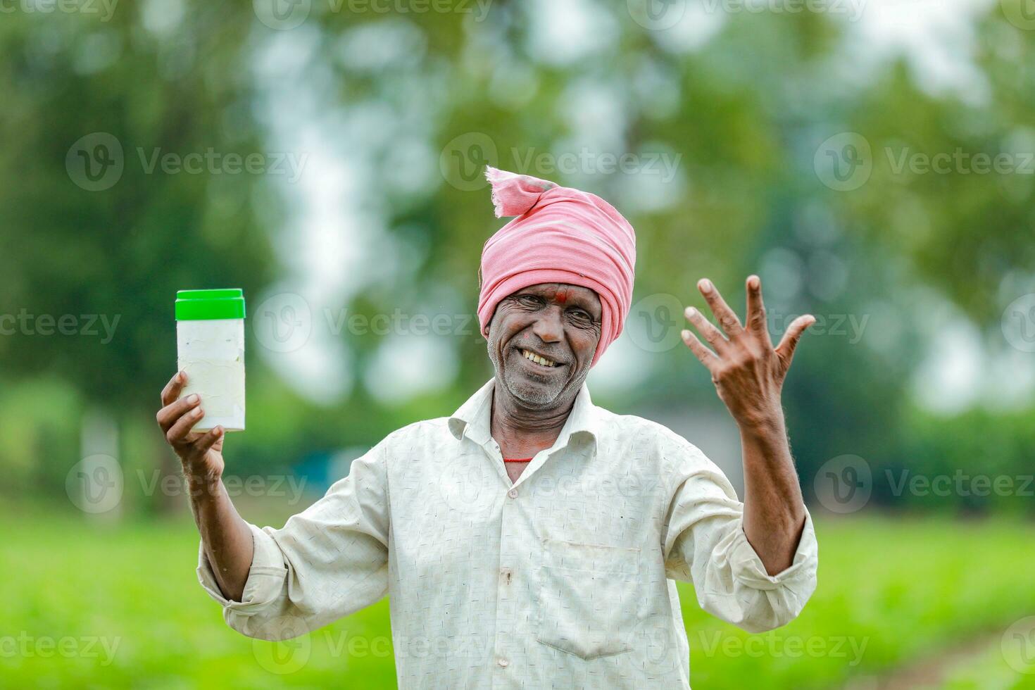 Indian happy farmer holding empty Bottle in hands, happy farmer showing white Bottle photo