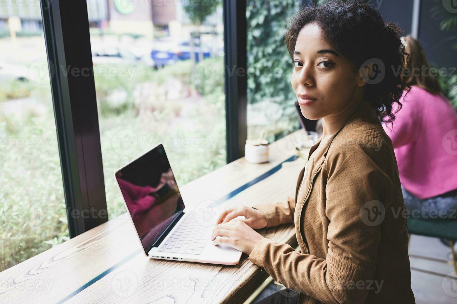 Young african woman doing school assignment on her laptop in cafeteria photo