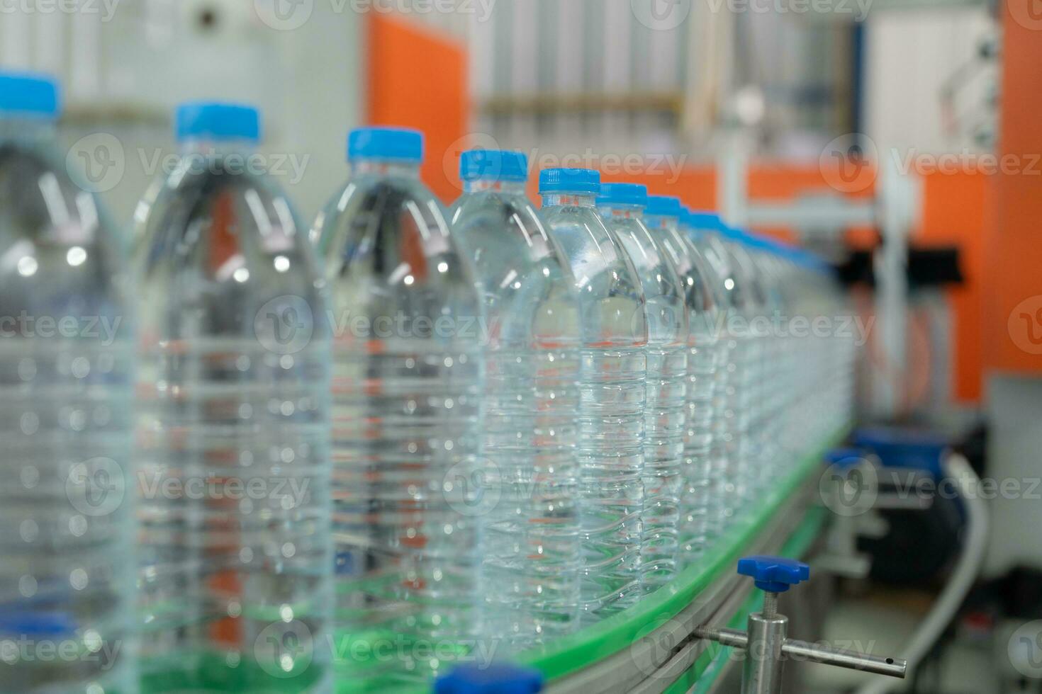 Water factory - Water bottling line for processing and bottling pure mineral water into blue bottles. Selective focus. photo