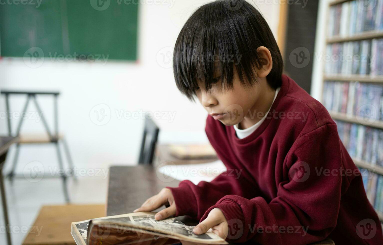 linda pequeño chico leyendo libro colegio niño alumno leyendo libro a escuela. niño haciendo tarea, sentado a mesa por libros, disfrutando interesante cuentos, leyendo fascinante aventurero novelas, Copiar espacio foto