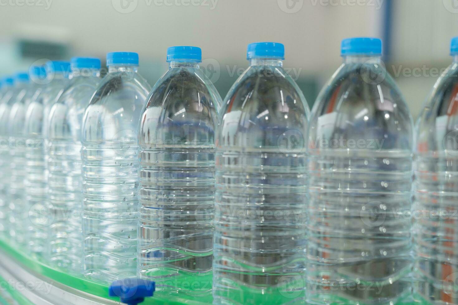 Water factory - Water bottling line for processing and bottling pure mineral water into blue bottles. Selective focus. photo