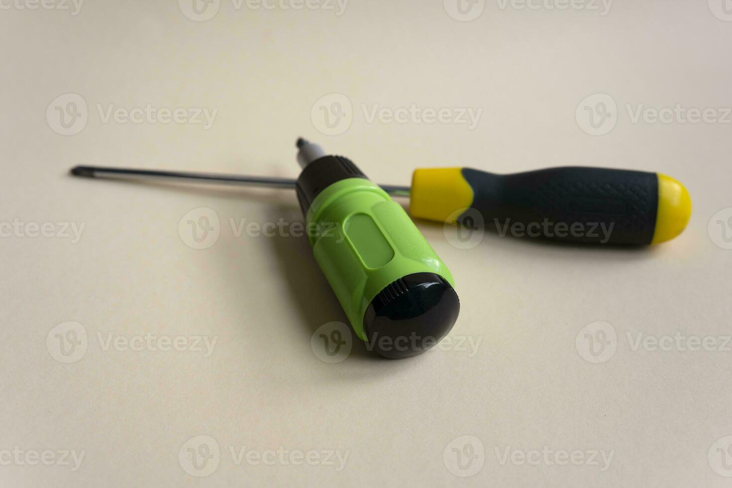 Two screwdrivers of different sizes. Two screwdrivers on a beige background. Two different screwdrivers. close-up. photo