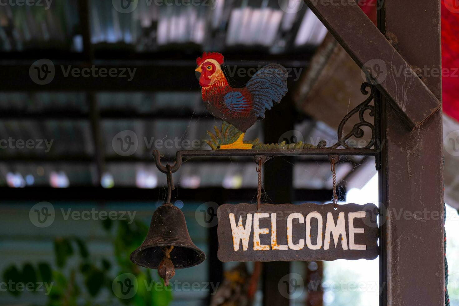 A welcome plaque with hanging bells and a rooster statue above. It's a classic badge. photo