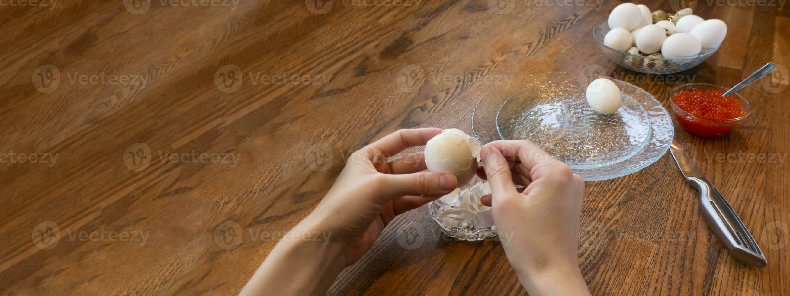 Woman peeling boiled egg on wooden background photo