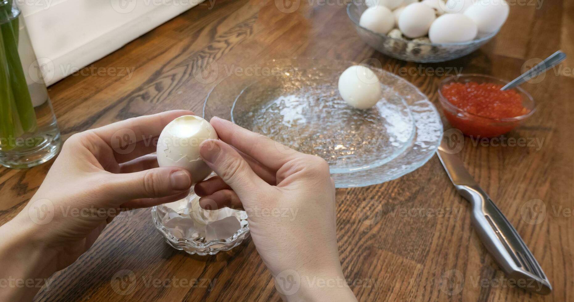 Woman peeling boiled egg on wooden background photo