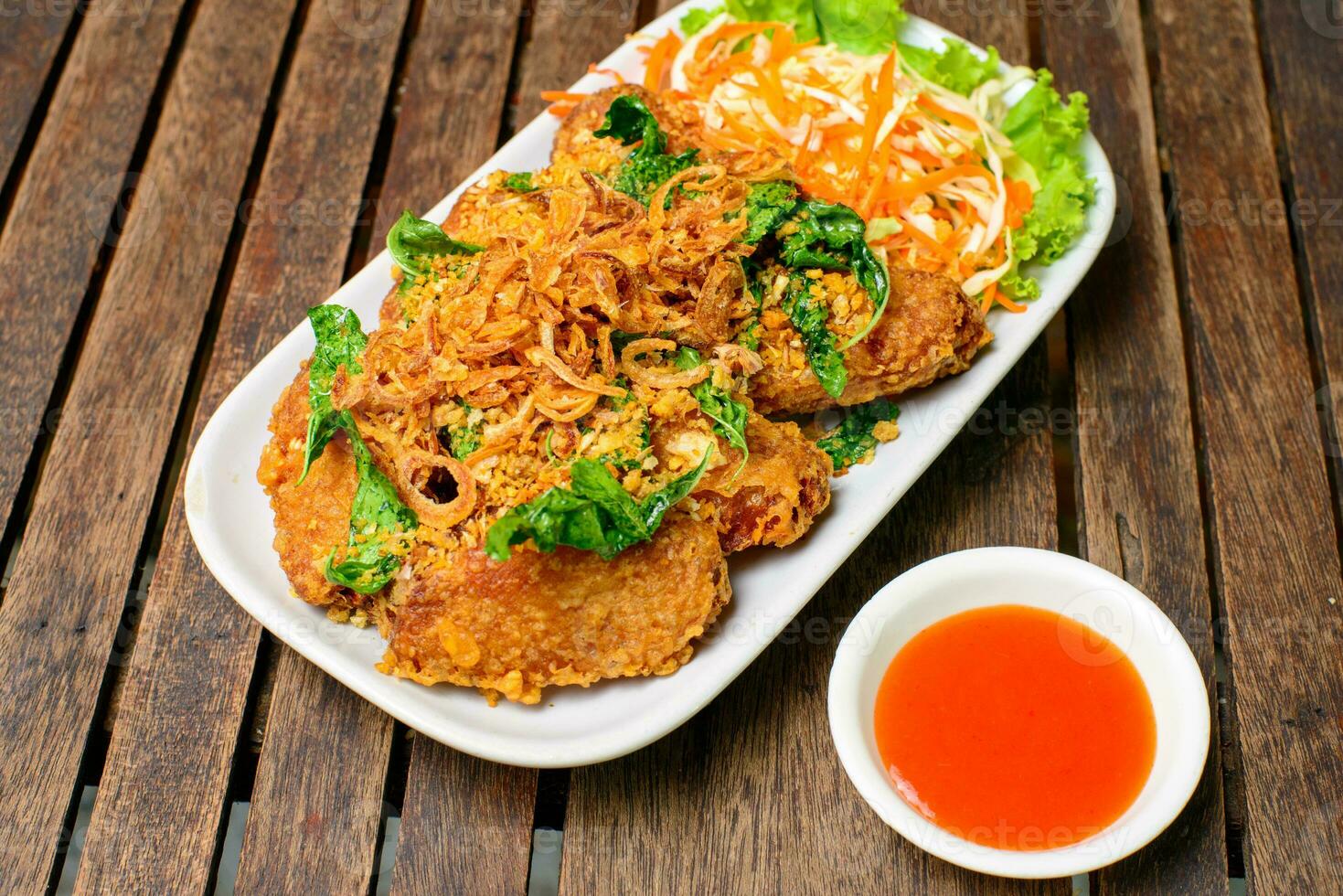 Fried chicken wing and fried herb on the wooden background. photo