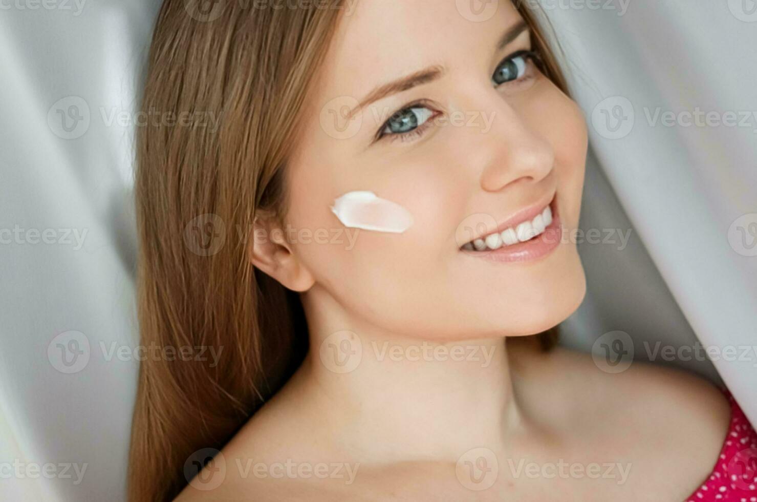 Beautiful woman with skincare cream on her face photo