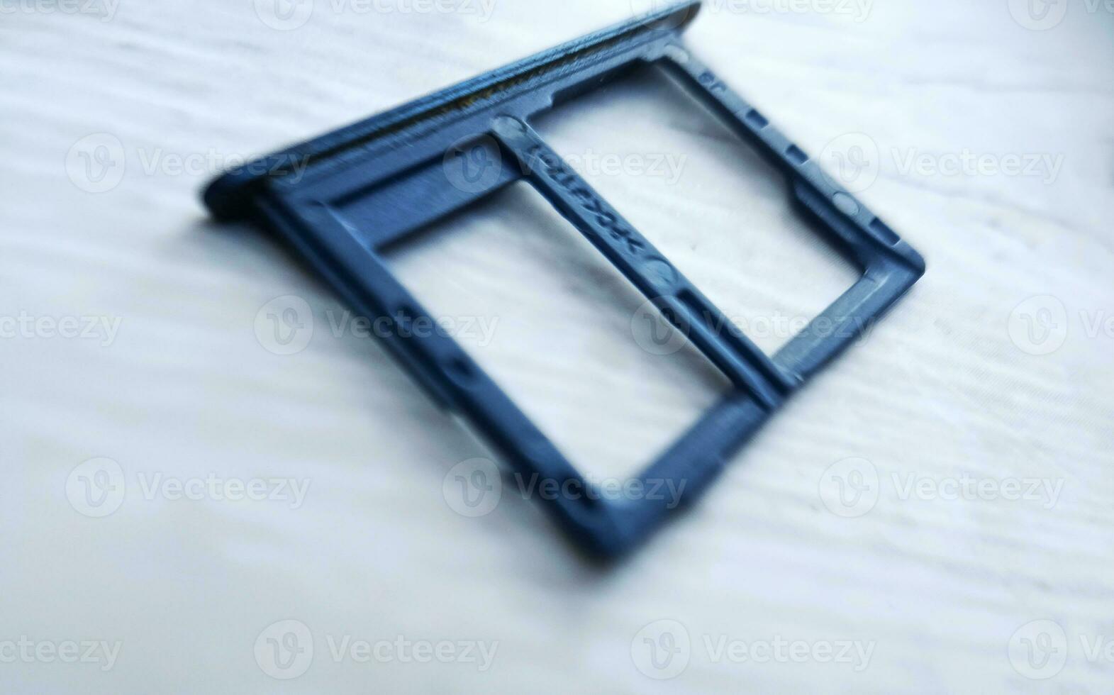 Close-up of a smartphone sim tray on a white wooden background. photo