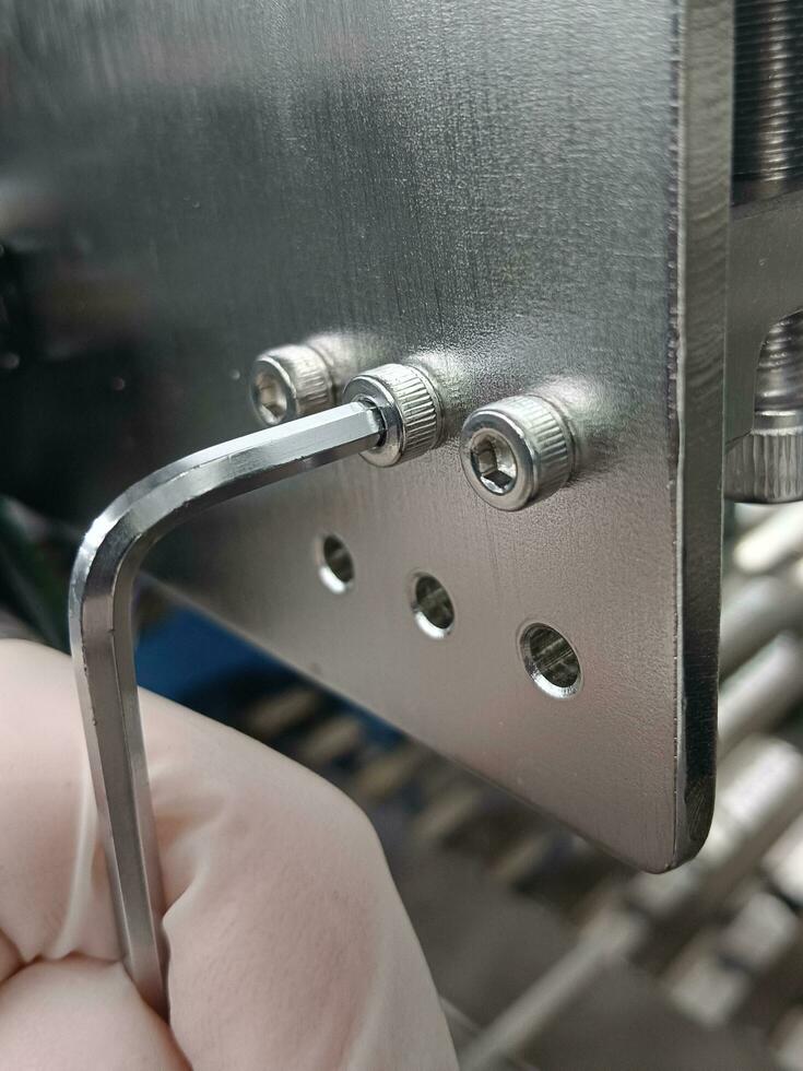 Hex wrench is unscrewing a nut made of stainless steel photo