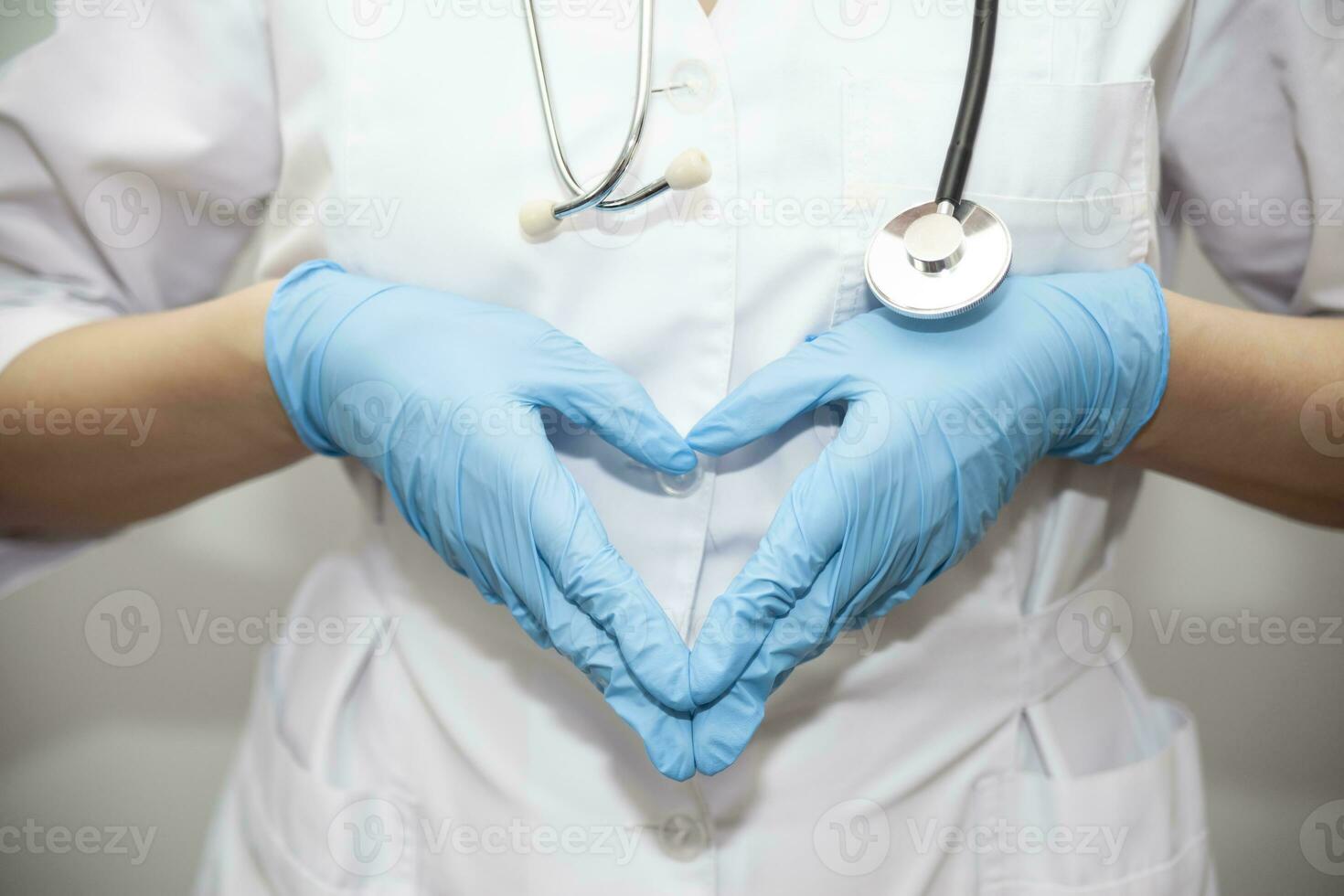 Woman with a medical mask and hands in latex glove shows the symbol of the heart. Doctor for the heart. Love to our pancreas. Love our medical professionals photo