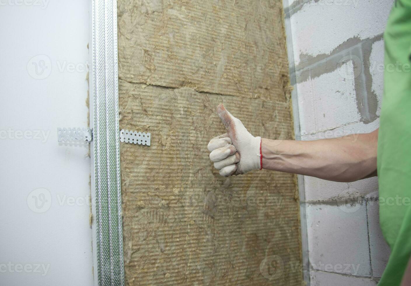 el trabajador aísla el paredes con mineral lana para más lejos revestimiento con cartón de yeso. calor aislamiento y sonido aislamiento de alojamiento foto
