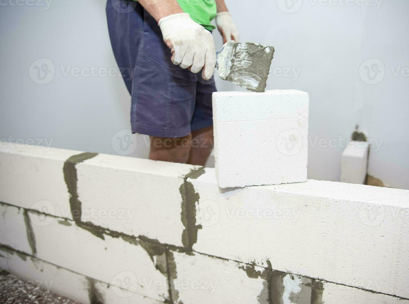 enlucido el pared.mano participación un espátula con construcción mezclar.aplicar  masilla o loseta pegamento a con ligero hormigón bloques.yeso el pared con  un masilla cuchillo.interno construcción 26542743 Foto de stock en Vecteezy