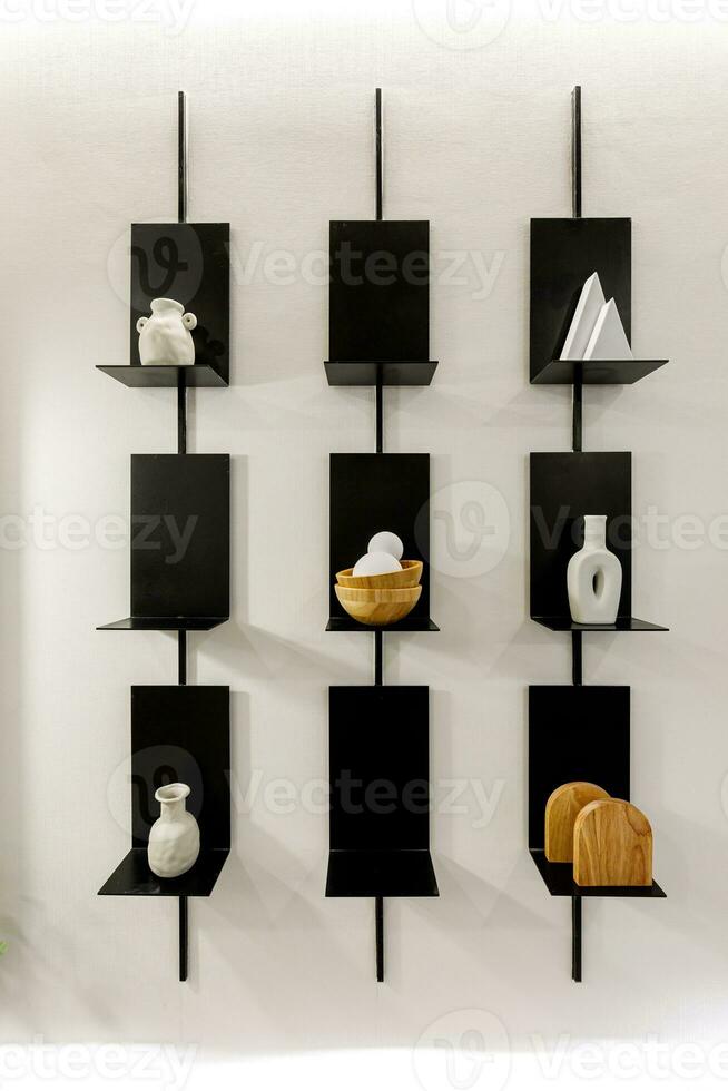 Black shelf hanging on white wall. Concept of storing stuff and keeping it organized with limited tools. photo