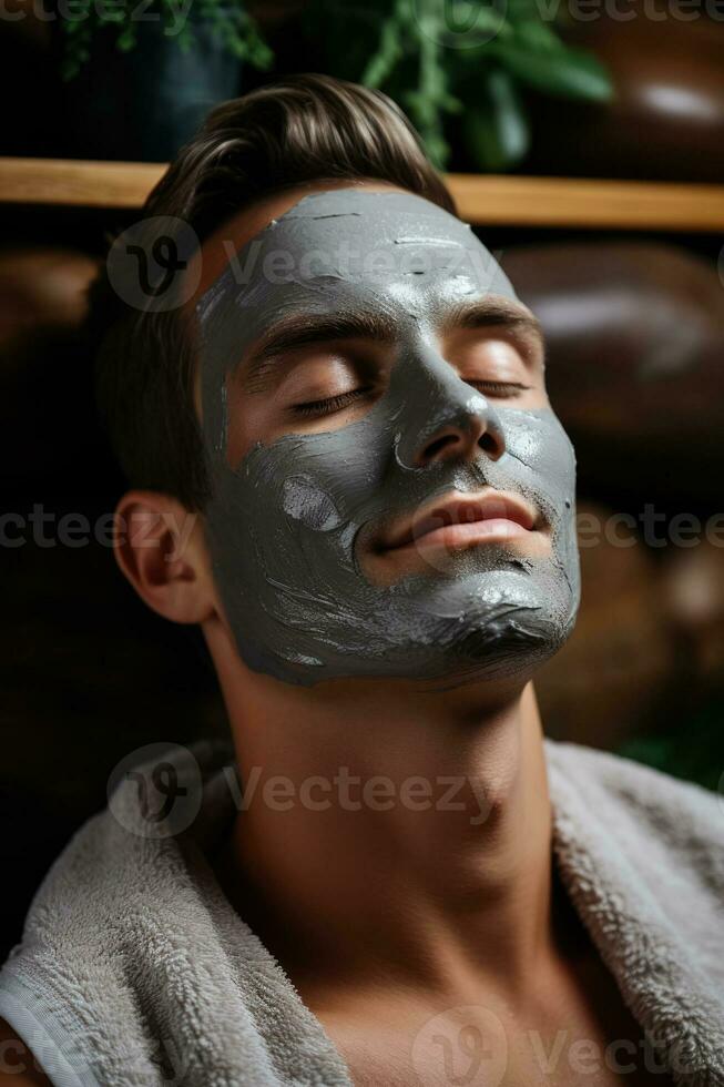 hermoso hombre con arcilla facial máscara en belleza spa foto