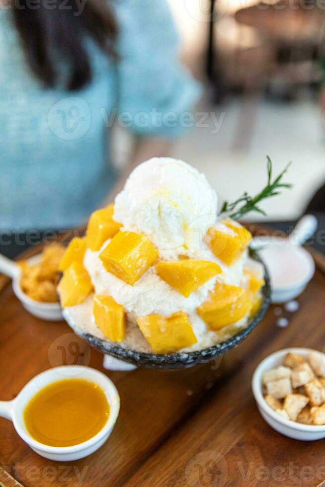 Shaved ice dessert with mango slices. Served with vanilla ice cream and whipped cream. Sweet dessert in Korean style. Local name, Bingsu. photo